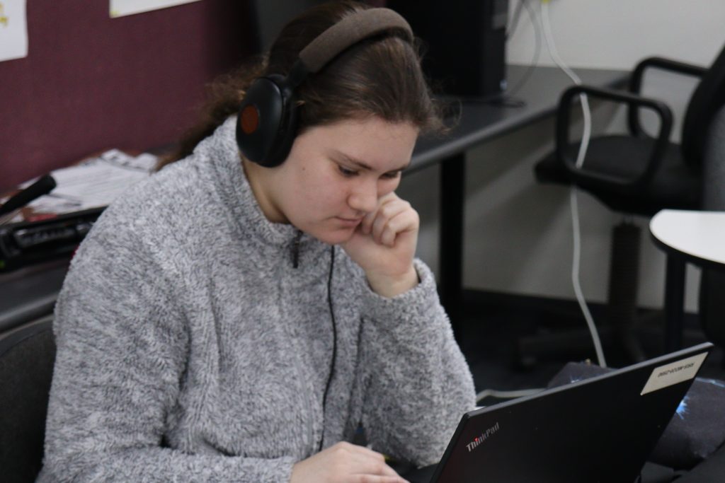 College student works on a laptop while using headphones. Image courtesy of Sheffield School 2021.